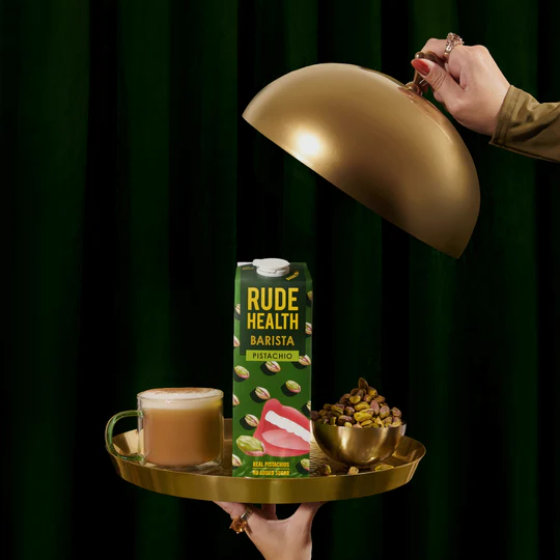 Rude Health Barista product on a tray with a gold lampshade against a dark green background