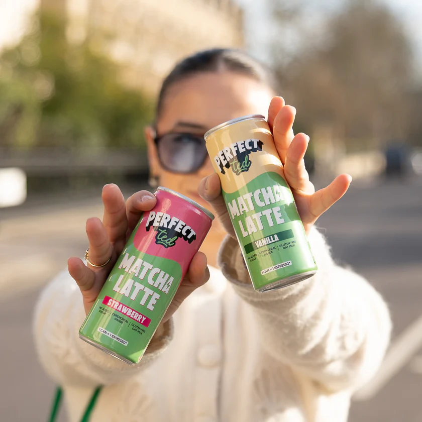 Person holding PerfectTed Matcha Latte Strawberry and Vanilla ready-to-drink cans outdoors