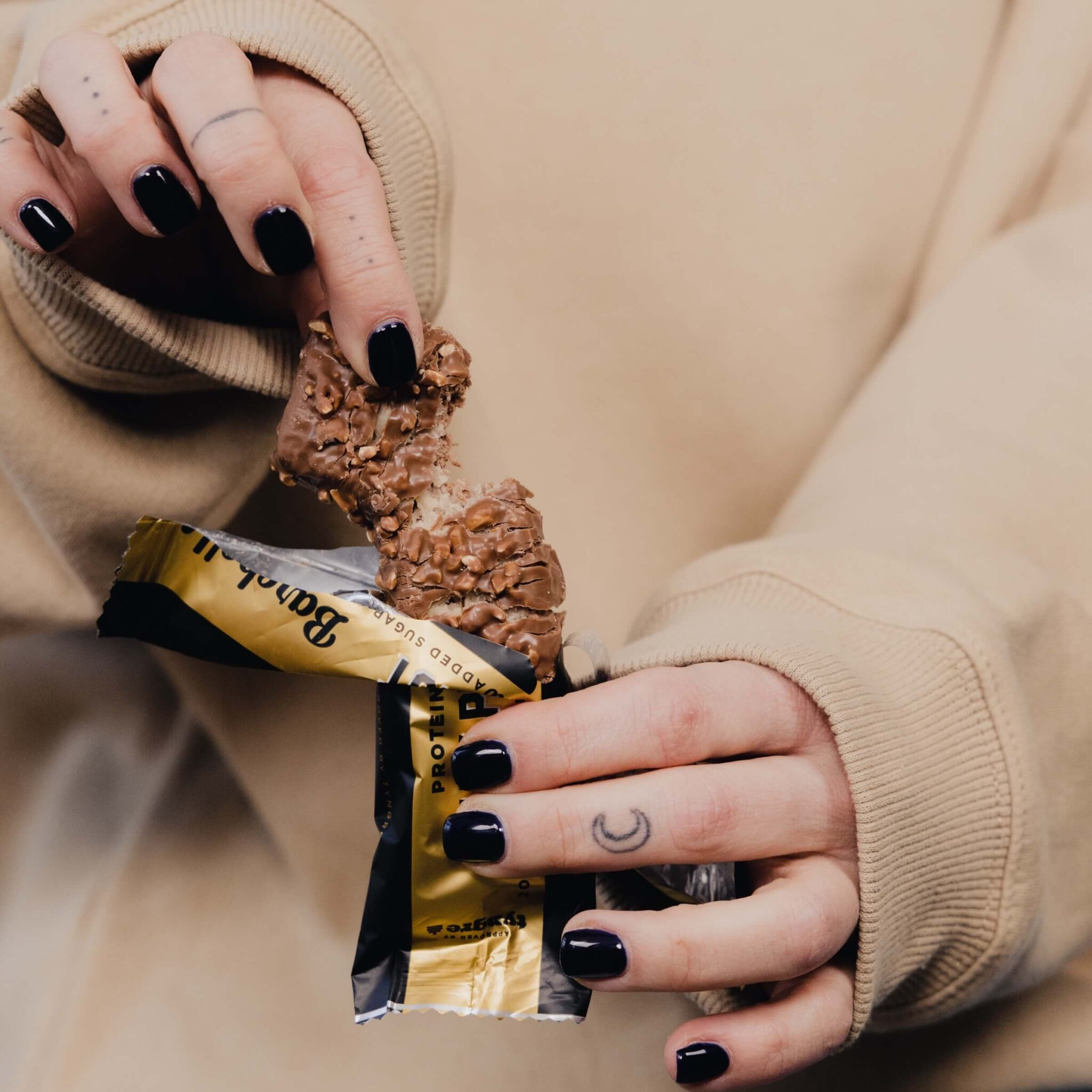 Person holding a chocolate bar with a focus on the hands and the product.