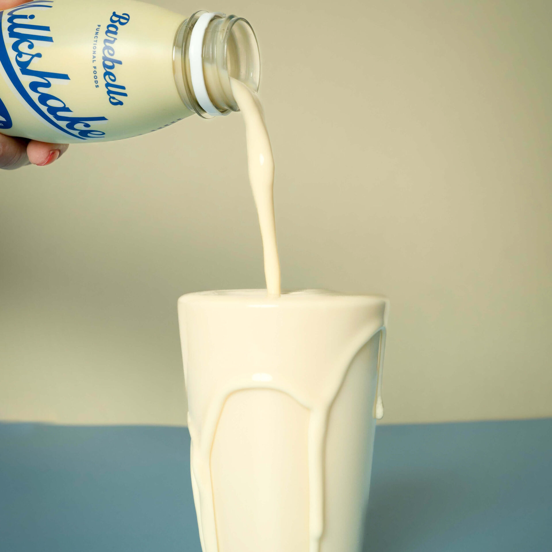 Bowl of Baskin-Robbins ice cream being poured into a cup with a bottle of vanilla ice cream.