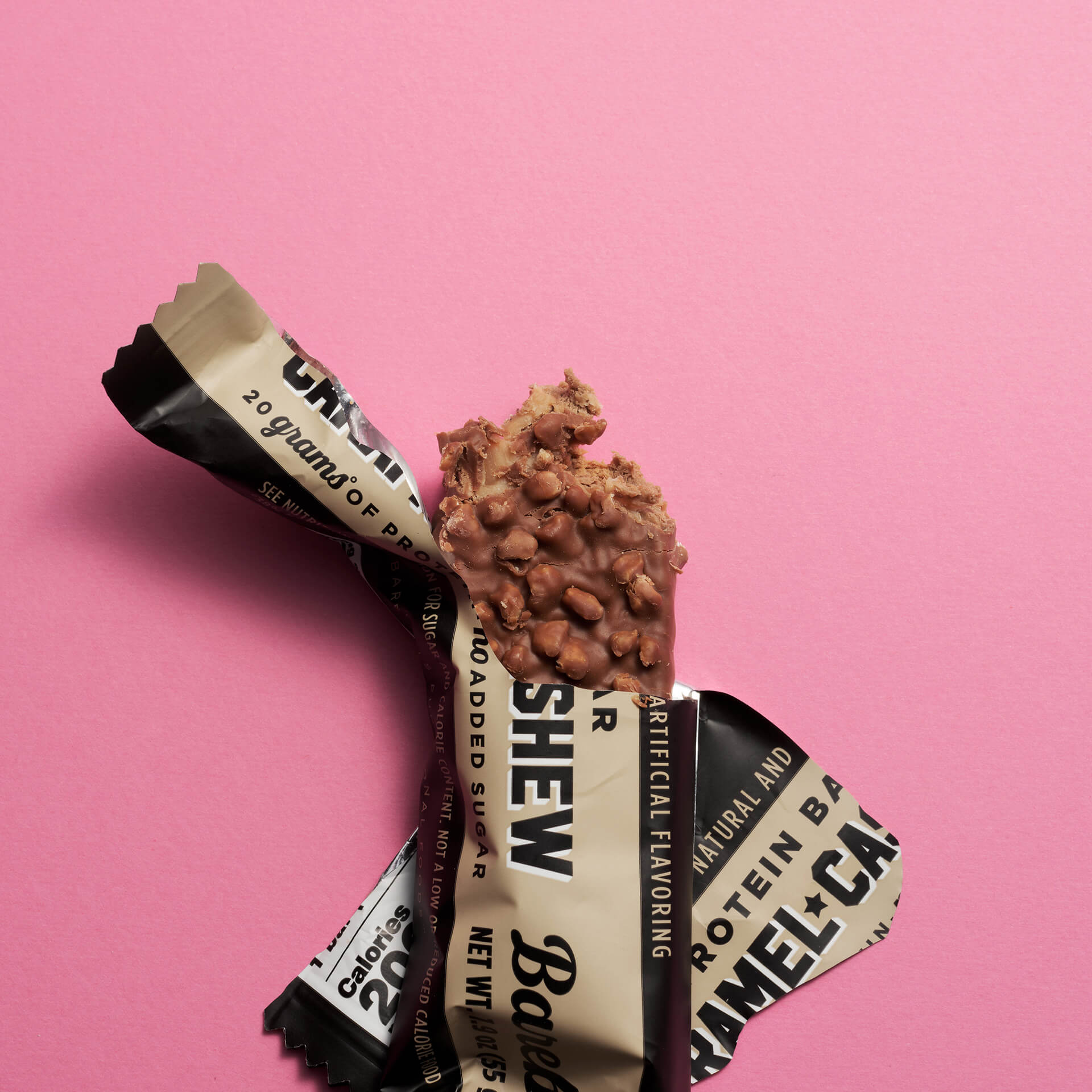 Bar of chocolate with a wrapper on a pink background