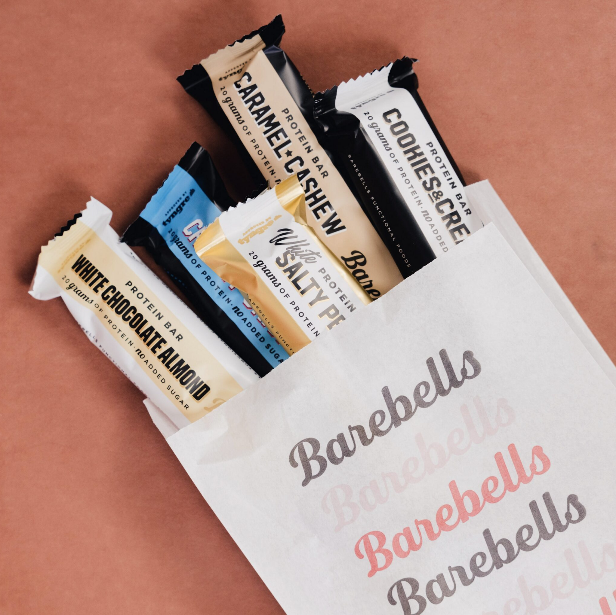 Assorted Barebells protein bars in a white bag on a brown background