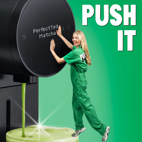 Woman in green pushing large PerfectTed Matcha dispenser with green matcha drink pouring out